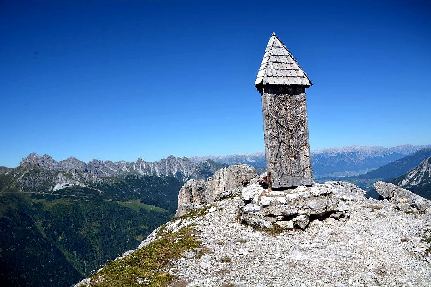 Hölzerner Bildstock auf einem Gipfel mit Blick auf die Kalkkögel